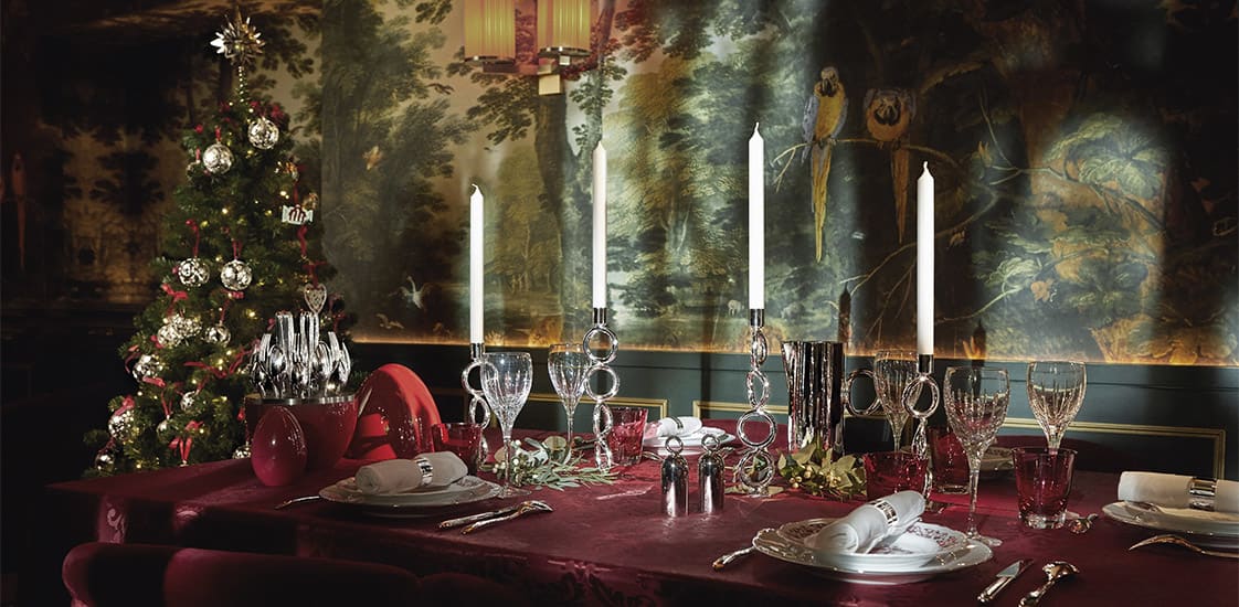 christmas table with candelabras on a festive red tablecloth and christmas tree